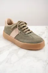 Zapatilla deportiva de cuero color verde oliva con detalles en rosa y suela marrón.