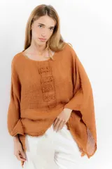 Blusa color ladrillo de lino con cuello redondo y mangas largas amplias. Presenta detalle de apliques rectangulares verticales en el frente.