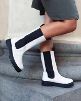 Botas blancas de caña alta con elástico lateral marrón y suela track negra.