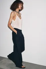 Pantalón de tiro medio color celeste confeccionado en hilatura con mezcla de lyocell. Tiene bolsillos laterales, pinzas delanteras, pierna ancha y cierre frontal con cremallera y botón.