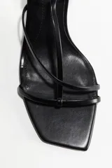 Sandalias negras de tacón fino con punta cuadrada y tiras finas sobre el empeine. Pulsera ajustable con hebilla de metal.