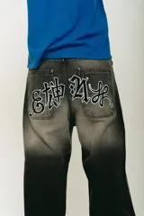 Pantalón jean negro de corte baggy con lavado localizado y aplique bordado en la parte trasera.