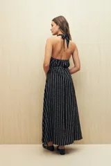 Vestido largo negro con estampado de líneas verticales blancas, escote halter y cintura con lazo.
