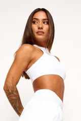Top deportivo blanco de cuello alto, sin mangas y corte ajustado.