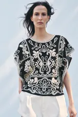 Top de Zara Woman Collection, color negro con apliques de crochet en color crudo. Cuello redondo y manga corta caída. Cierre en la espalda con abertura y botón.