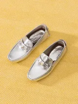 Mocasín de cuero vacuno color marrón con textura croco y acabado brillante. Incluye aplique metálico en forma de corazón sobre el frente y suela de goma.