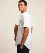 Camisa blanca de lino con cuello mao, manga corta y abotonadura parcial.