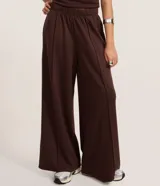 Pantalón de mujer color marrón oscuro, de tiro alto con cintura elástica fruncida y corte ancho recto. Presenta vincos delanteros marcados.