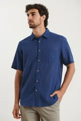 Camisa sport de manga corta color verde oliva, línea premium, con cuello clásico, cierre frontal con botones de coco y bolsillo de parche en el pecho. Confeccionada en lino y algodón.