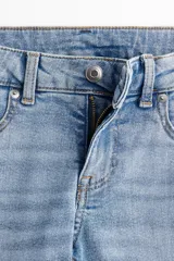 Pantalón de jean de tiro bajo, corte ajustado en cintura y muslos, y acampanado desde la rodilla hasta el ruedo. Confeccionado en denim ligeramente elástico. Cuenta con cierre y botón, bolsillos delanteros decorativos, bolsillo monedero y bolsillos traseros. Largo estándar.