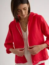 Chaqueta roja de lino, con capucha, corte holgado y bolsillos laterales.