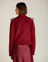 Chaqueta corta color borgoña, estilo motociclista, con cierre cruzado y cinturón con hebilla.