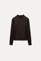 Camiseta blanca de manga larga con cuello alto y corte ajustado.