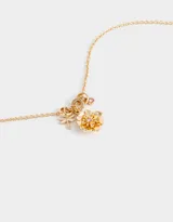 Collar corto dorado con cadena de eslabones y dijes colgantes: libélula, anillos y flor con centro de cristal rosado.