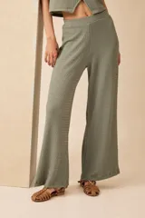 Pantalón palazzo color verde oliva, de tela de punto arrugada con cintura alta y corte amplio.