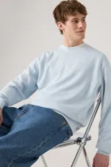 Sweater celeste de cuello redondo y corte holgado, con logo pequeño bordado al tono en el pecho.