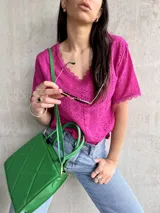 Blusa de broderie en color fucsia, con escote en forma de V y mangas cortas.