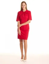 Vestido midi verde de crepe, con cuello a la base, escote entrelazado, mangas cortas y cierre invisible en la espalda con tajo en el ruedo.