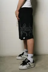 Bermuda negra de algodón con corte oversize y logo trigrama bordado en blanco en la pierna derecha.
