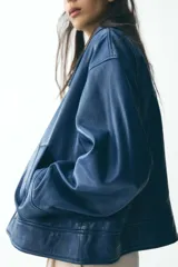 Cazadora azul de piel con cuello solapa, manga larga, bolsillos de vivo en delantero y cierre frontal con cremallera.