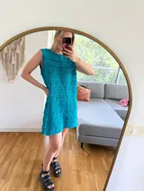 Vestido corto turquesa tejido en algodón con lurex, sin mangas y calado.