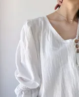 Camisa blanca de mangas 3/4 con detalle de volados en los puños y botones de madera.