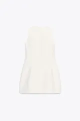 Vestido corto blanco de cuello redondo y sin mangas. Falda con pliegues y volumen. Cierre trasero con cremallera oculta.