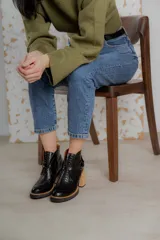 Botas cortas de cuero negro con textura tipo cocodrilo, caña alta, cierre con hebilla y taco de madera.