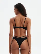 Conjunto de bikini negro, con corpiño tipo push-up con tirantes finos y bombacha de corte bajo con tiras cruzadas en la cintura.