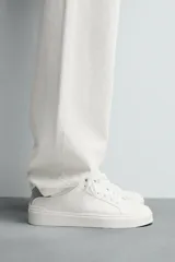 Zapatillas deportivas blancas de caña baja con detalle de color gris en el talón y suela con volumen.