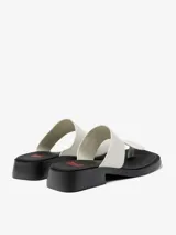 Sandalias de cuero vacuno color blanco, con tira ancha sobre el empeine y tira entre los dedos. Suela plana color negro.