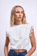 Remera blanca de algodón con mangas cortas y detalle de encaje calado en los hombros.