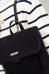 Mochila estructurada negra con frente en gamuza y cuerpo en símil cuero texturizado. Tiene asa superior y correas regulables.