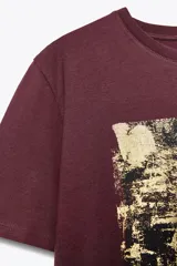 Camiseta de cuello redondo y manga corta color borgoña con estampado metalizado en el frente.