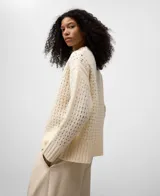 Jersey de lana cocida color crudo, con cuello perkins y manga larga. Presenta un punto calado con textura de rejilla en el cuerpo y punto canalé en puños y bajo.