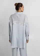 Camisa celeste de corte recto con bordados blancos.