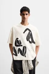 Camiseta color crudo de corte relaxed fit, cuello redondo y manga corta. Presenta un estampado abstracto con figuras humanas en color negro.