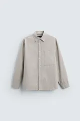 Camisa de manga larga con cuello solapa y bolsillo plastrón en el pecho. Diseño a cuadros pequeños en tonos beige y gris.