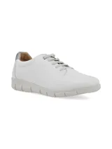 Sneaker de cuero blanco con talón dorado, cordones finos y suela beige con diseño anatómico.