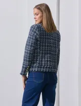 Chaqueta tipo blazer en tejido tweed azul con detalles en blanco y lurex. Tiene escote mao, abertura central, bolsillos delanteros y puños con aplique de botones perlados. Terminación desflecada y forro interno.