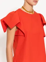 Top color naranja con cuello redondo y mangas cortas con volados.