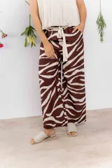Pantalón palazzo marrón con estampado de cebra en blanco, tiro alto y lazo en la cintura.