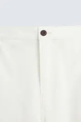 Pantalón de jean color blanco, corte recto, con bolsillos frontales y traseros, y cierre frontal con cremallera y botón.