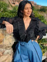 Camisa de organza negra con volados en el frente y mangas abullonadas.