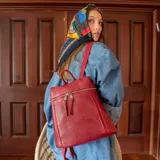 Mochila roja de símil cuero con apertura frontal y cierre metálico, detalle de grabado láser y costuras al frente, bolsillos internos, correas de galón regulables y asa de mano.