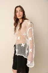 Camisa blanca de crochet con mangas largas y botones frontales.