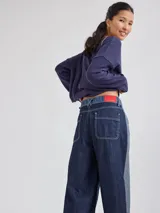 Pantalón ancho de denim con diseño patchwork en diferentes tonos de azul, con tiro alto, corte holgado y cierre frontal con botones.
