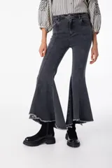Pantalón de jean elastizado negro con corte acampanado y volados en el ruedo.