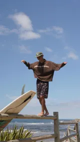 Buzo de tejido marrón con cuello polo y cierre parcial. Presenta un patrón texturado de espiga y el estampado frontal en blanco con el texto "glassywave".