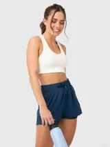 Top deportivo blanco con soporte medio, almohadillas removibles y detalles de encaje en tirantes y bajo busto. Espalda con tirante grueso central.